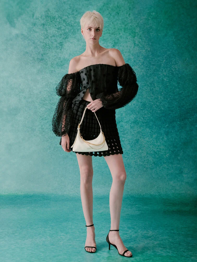 Black off-shoulder top paired with a patterned skirt and mid heels, one of many casual wedding guest outfit options.  