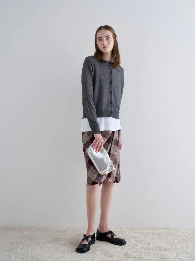 Clutch yang digenggam secara vertikal di samping dengan ibu jari di belakang, cara yang berbeda untuk membawa tas kecil.